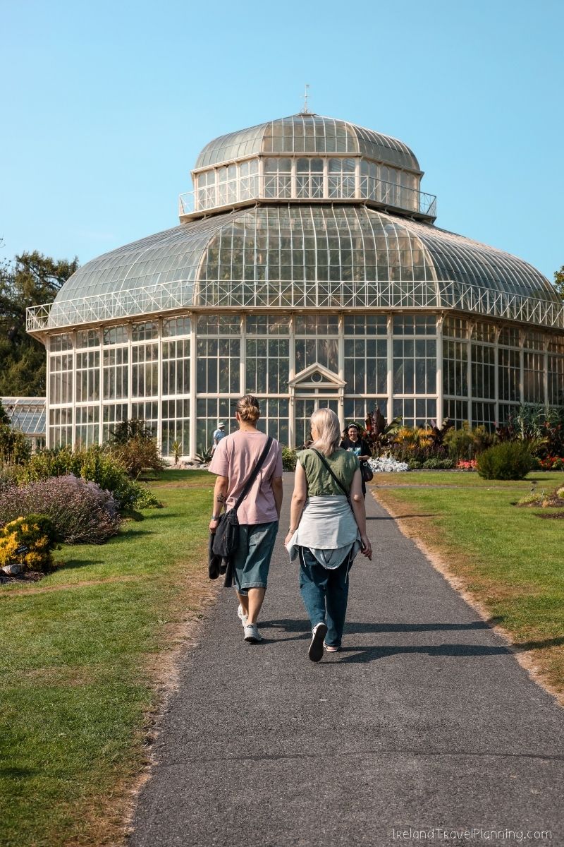 Two women walk towards the National Botanic Gardens glasshouse in Dublin.