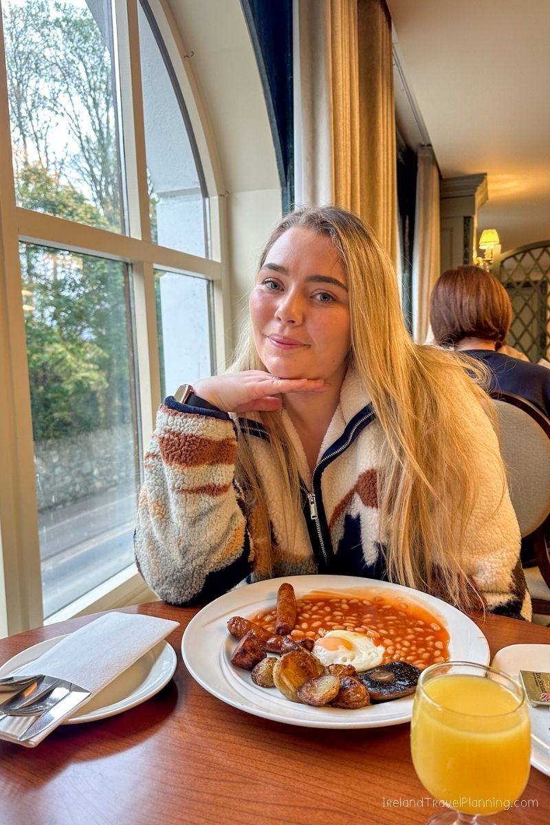 Woman enjoying a hearty Irish breakfast in Ireland, a travel tip.