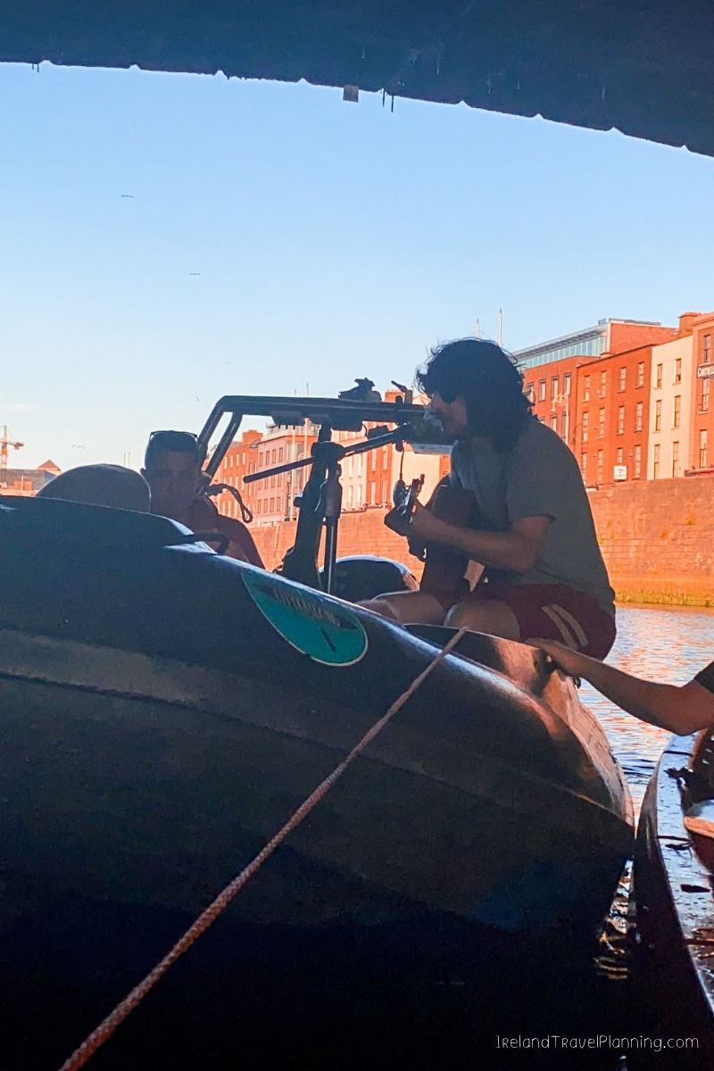 Musician playing guitar on a boat in Ireland, one of many Ireland travel tips.
