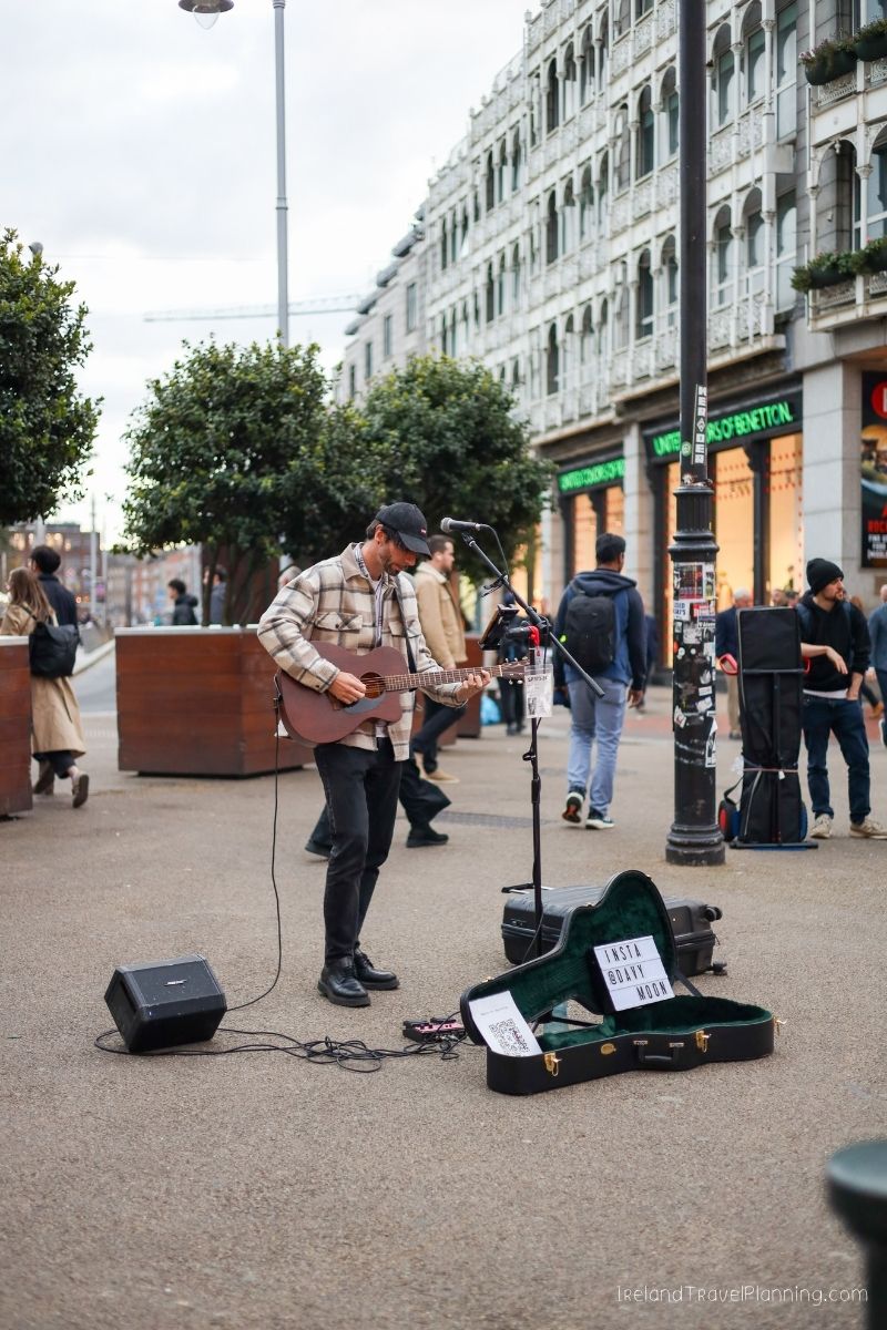 Street musician playing guitar in Ireland, a travel tip for experiencing local culture.