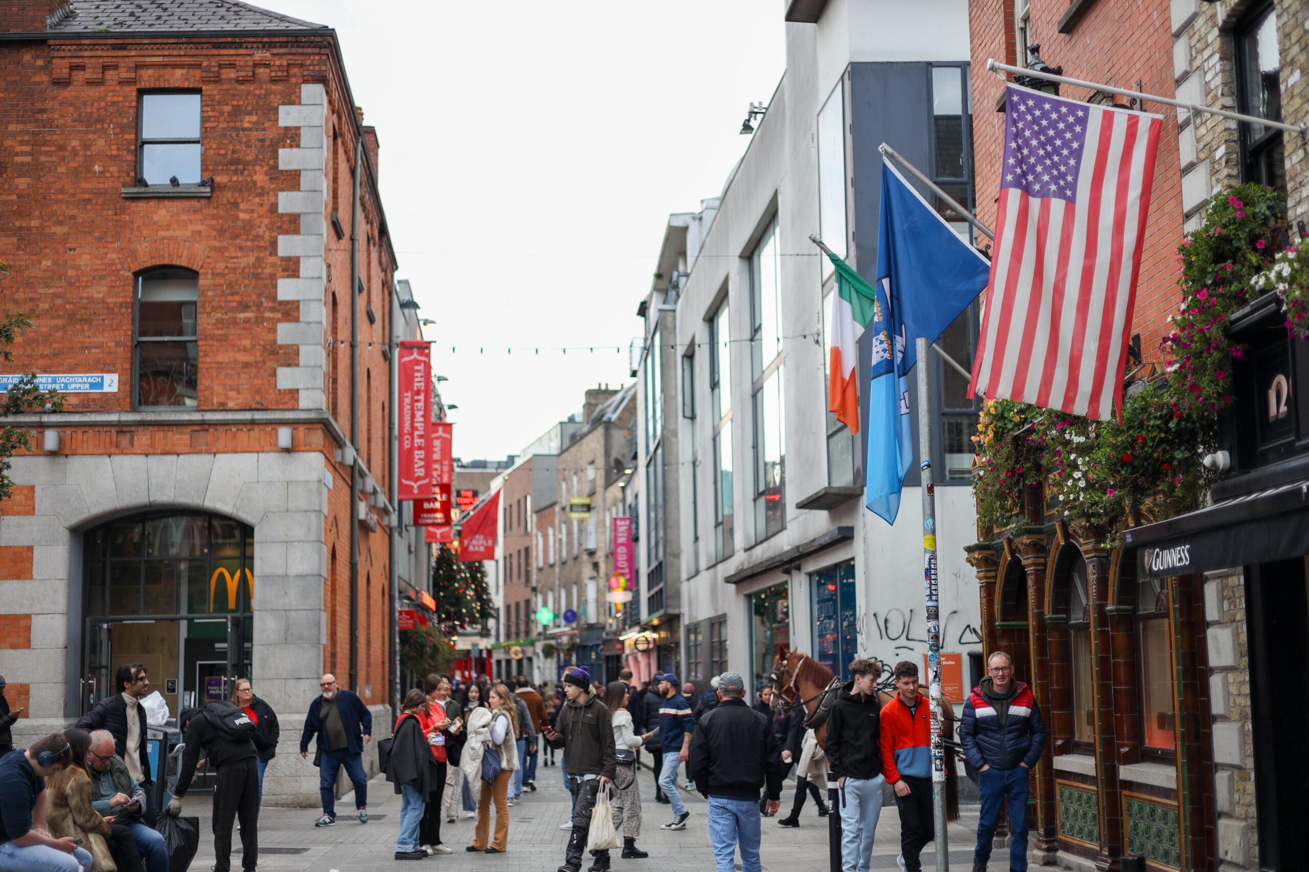People on a street in Dublin, Ireland, with flags and shops. Free things to do.