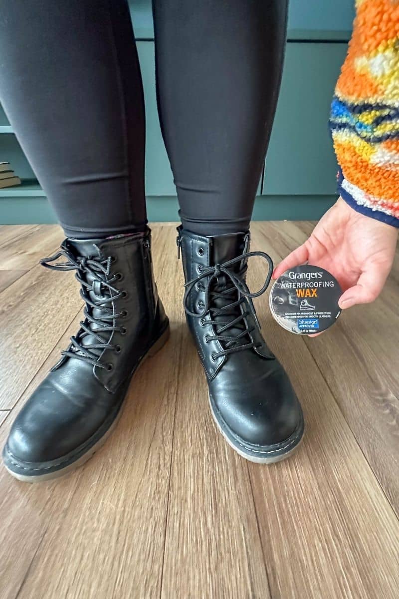 Woman applying Grangers waterproofing wax to black leather boots for Ireland travel.