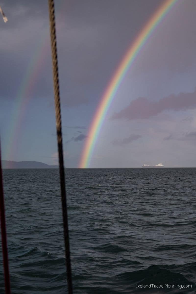 Double rainbow over the sea in Ireland with a ship in the distance.