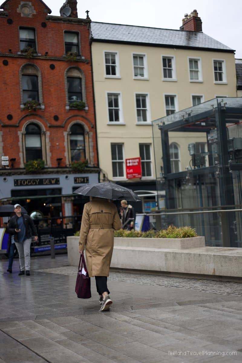 Woman with umbrella walks past Foggy Dew pub, Ireland travel tip