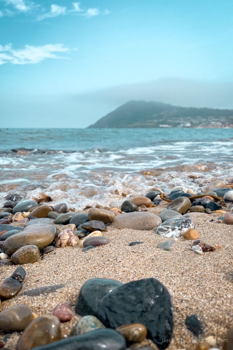 Pebble beach with waves and a misty mountain in the distance, a free Dublin activity.
