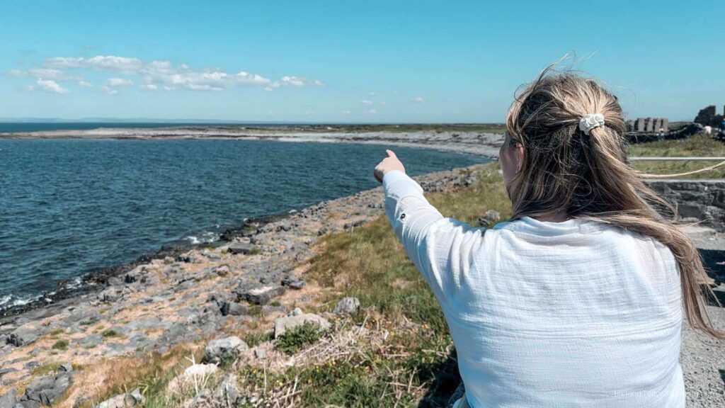 Woman pointing to Inis Mór coastline. Things to do on Inis Mór include exploring the Aran Islands.