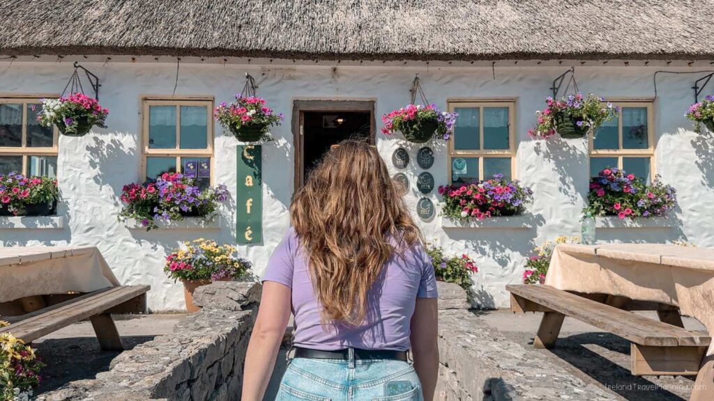 Woman approaches a charming thatched-roof café on Inis Mór, Aran Islands.