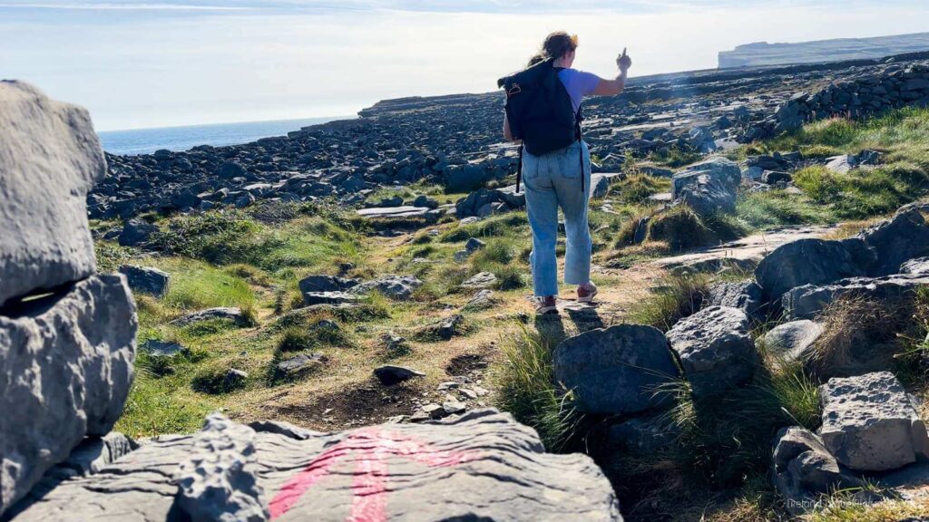Hiker on Inis Mór, Aran Islands, with rugged coastline views.