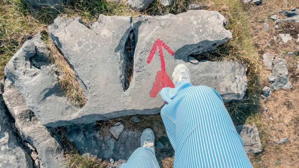 Red arrow trail marker on rock, Inis Mór. Hiking on the Aran Islands.