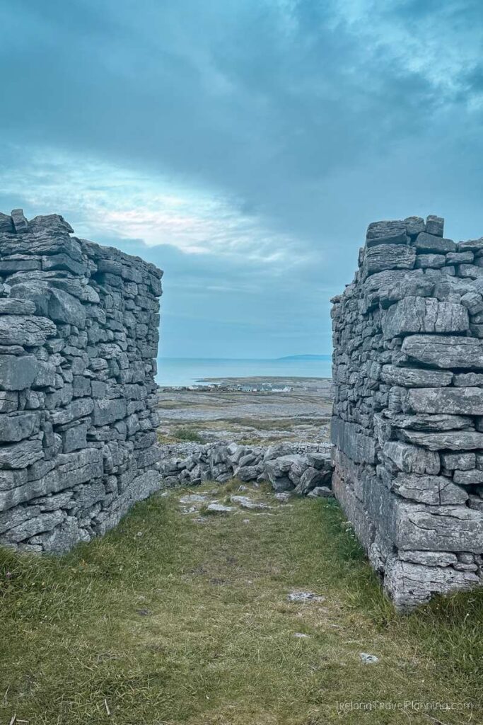 Stone walls framing Inis Mór island view. Things to do on Inis Mór include exploring ancient sites.
