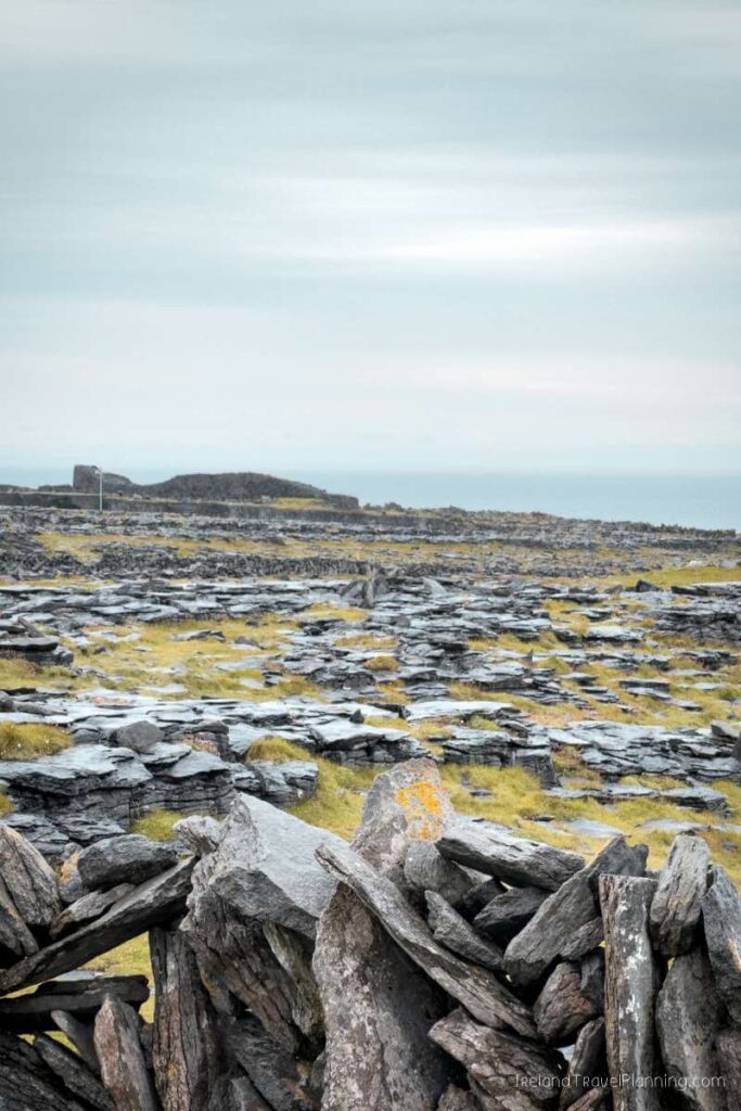 Inis Mór landscape with stone walls and Dún Aonghasa in the distance.