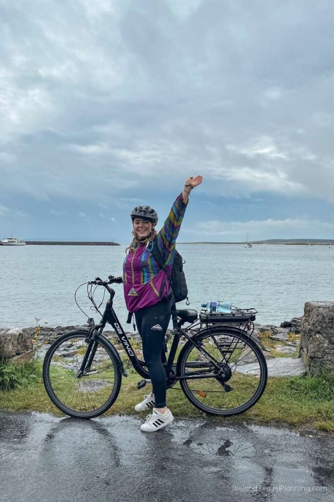 Woman biking on Inis Mór, Aran Islands, with ocean view.