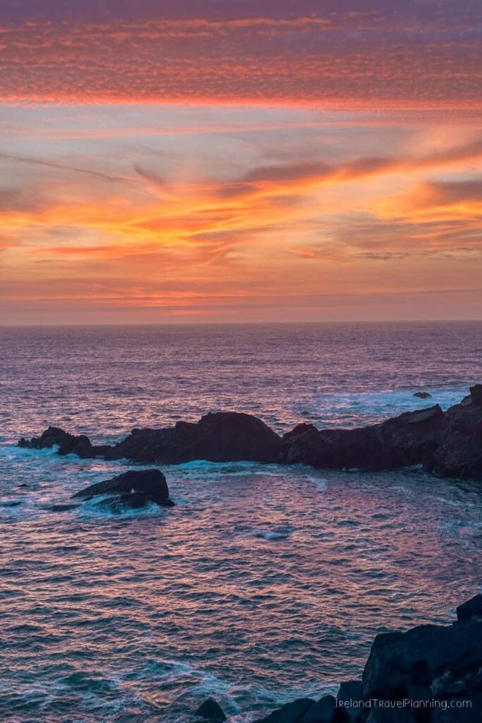 Kerry coast at sunset: Orange sky over ocean and rocky shore.