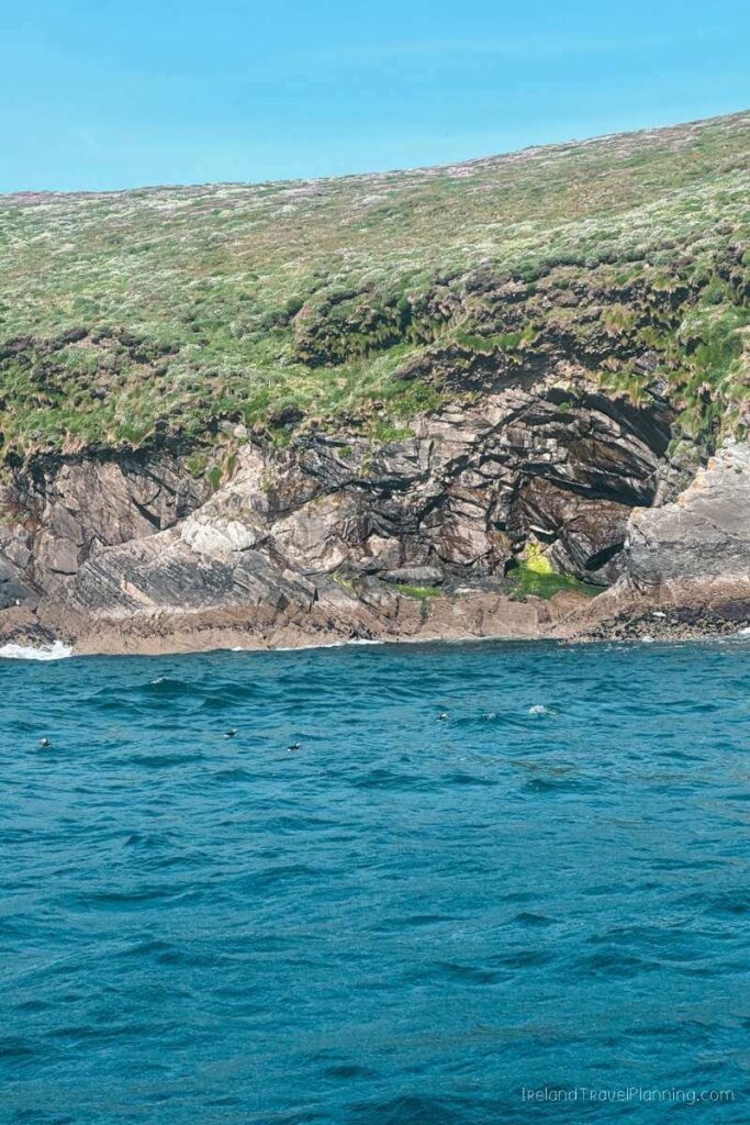 Rocky coastline in Kerry, Ireland, with a cave and blue water.