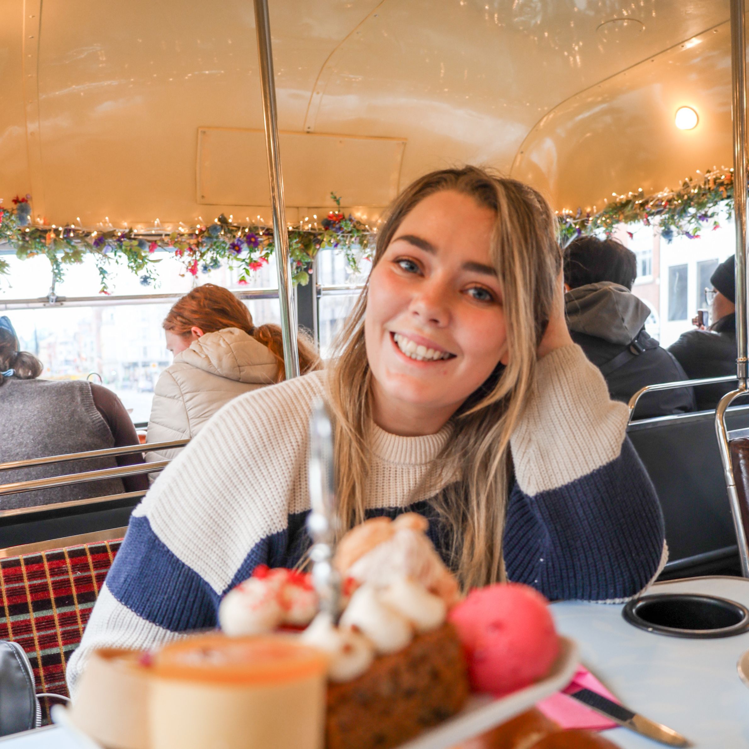 Woman enjoying afternoon tea in a decorated bus, a fun Ireland experience.