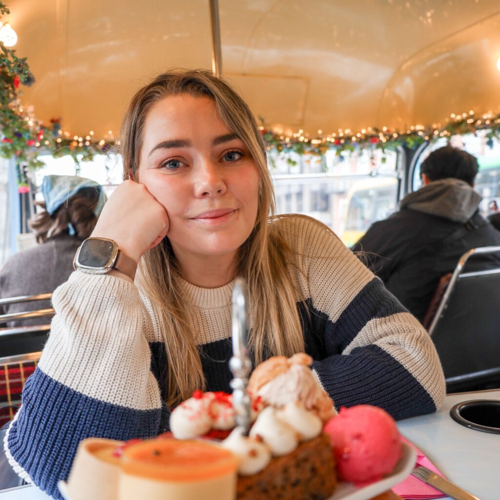 Woman enjoying afternoon tea on a festive bus, a great experience when driving in Ireland.
