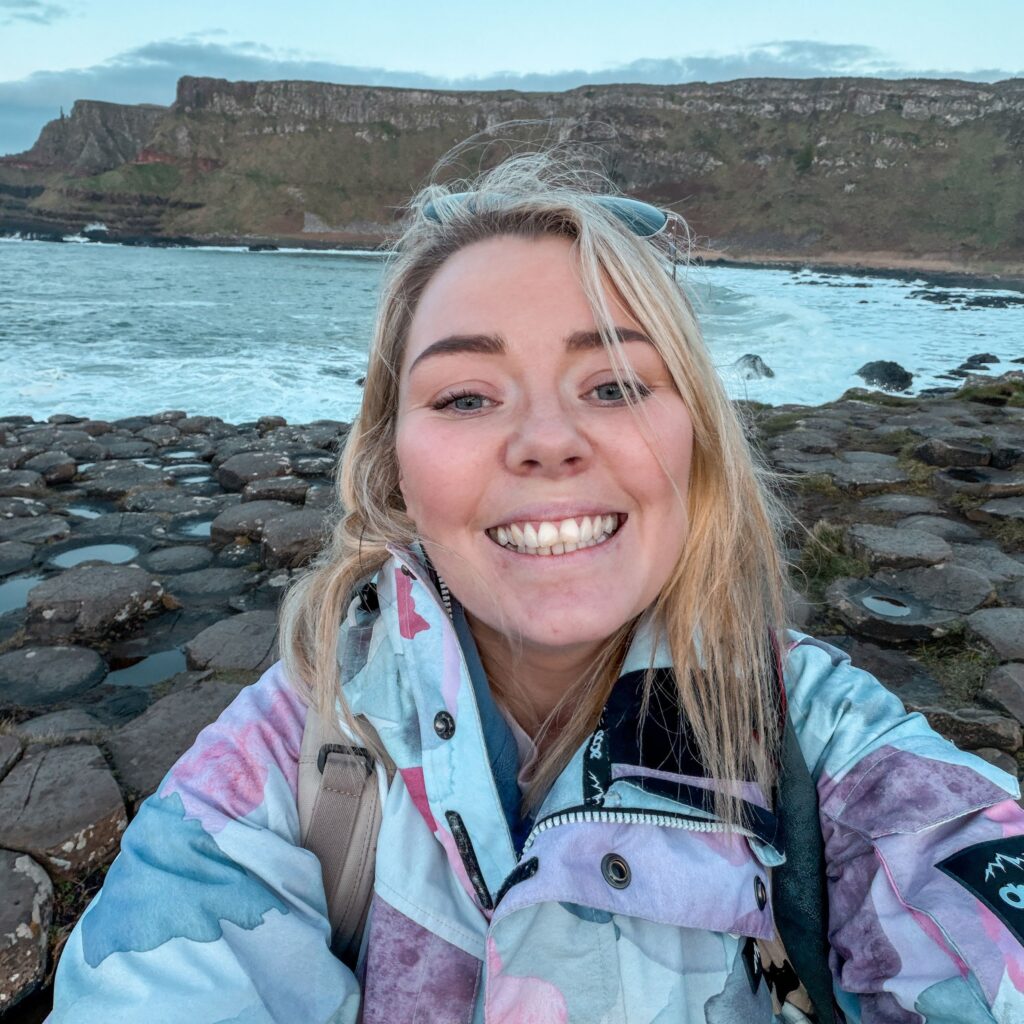 Woman smiles at Giant's Causeway, a popular Ireland driving destination.