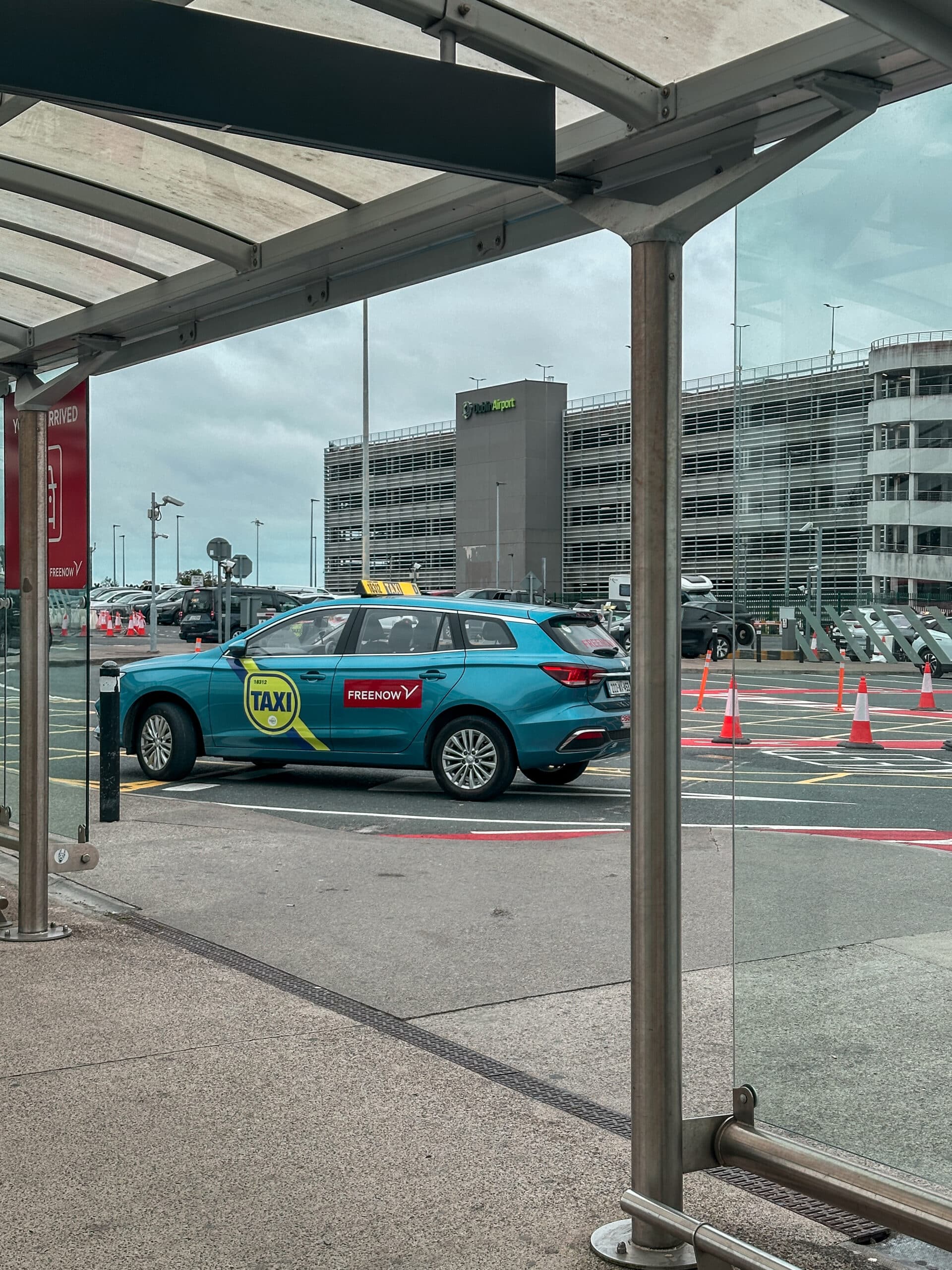 Blue taxi with "FREE NOW" and "TAXI" logos at Dublin Airport, a public transport option.