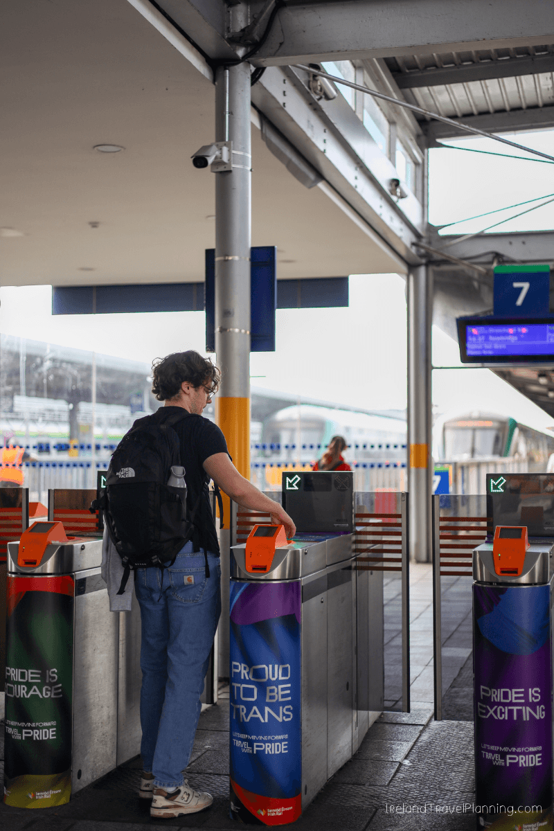 Man using ticket gate at Dublin public transport station with Pride art.