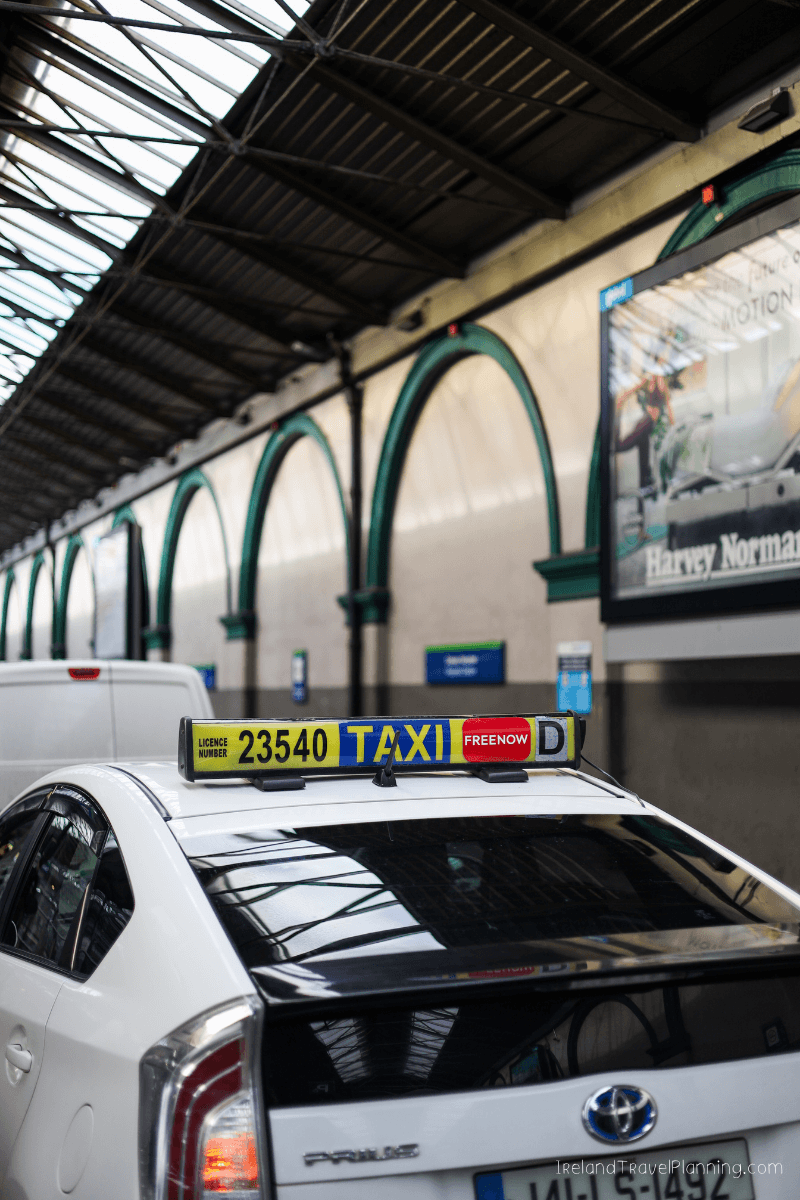 White taxi in Dublin with "23540 TAXI" sign, indicating public transport options.
