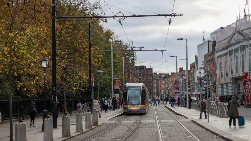 Dublin tram at a stop, people waiting. Public transport in Dublin.