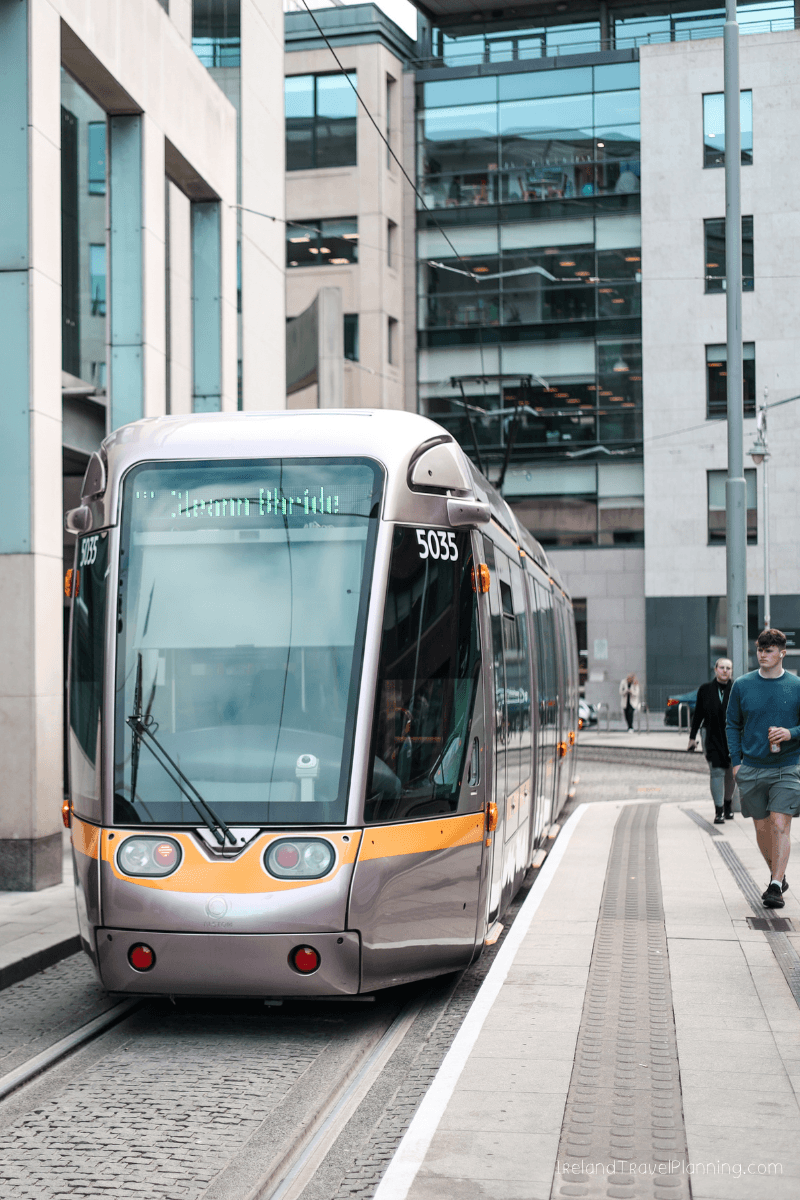 Luas tram, part of public transport in Dublin, arriving at a stop.