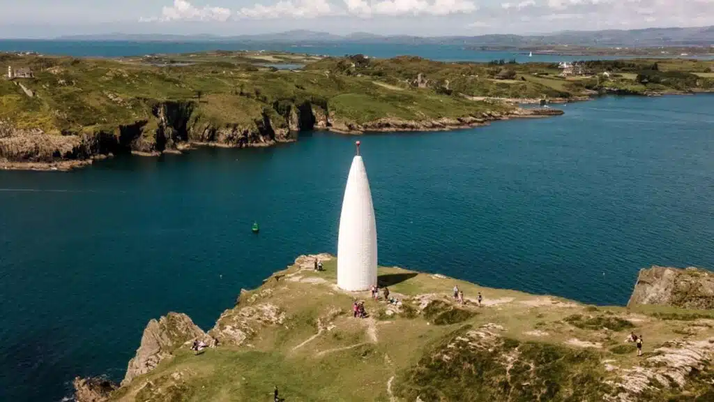 White obelisk on Baltimore Beacon, Coastal scenery with cliffs and blue water.
