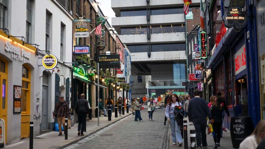 Cobblestone street in Dublin with colorful shop signs and pedestrians, a hidden gem in Dublin.