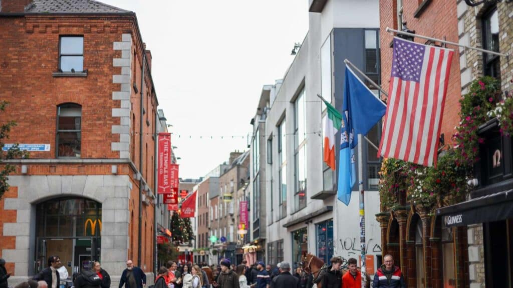 Dublin street scene with US and Irish flags, a Temple Bar banner, and pedestrians.