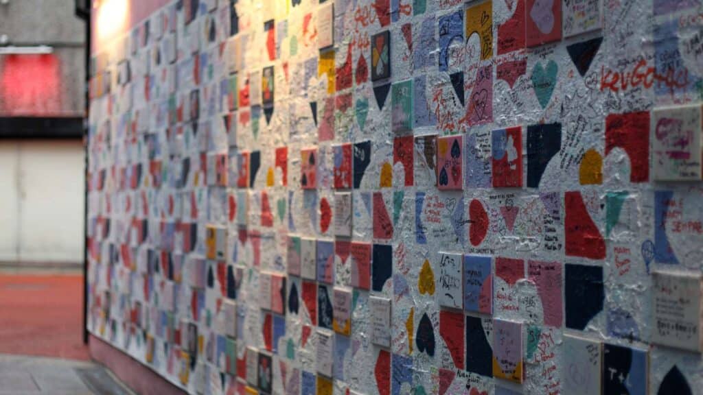Wall covered with colorful tiles and handwritten messages, a hidden gem in Dublin.