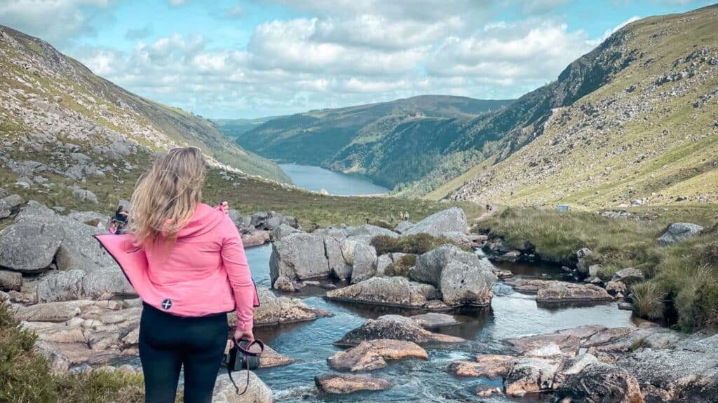 Woman overlooking scenic Glendalough valley and lake in Ireland.