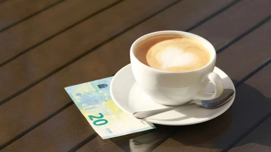 Cappuccino with latte art, 20 Euro bill on a table. Tipping in Ireland concept.