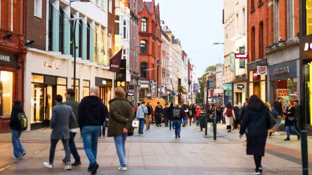 Crowded Grafton Street, Dublin, with shops like BOSS and Levi's.