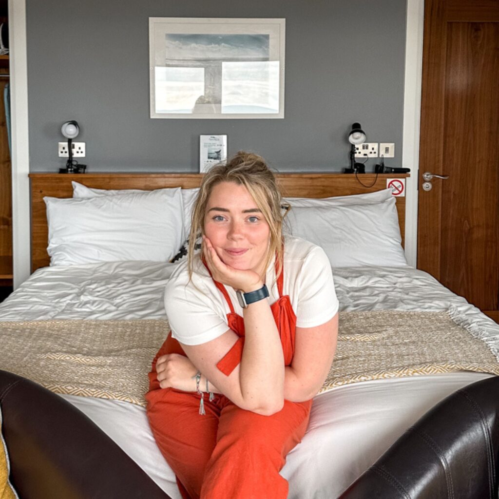 Woman in orange overalls on a bed in a hotel room, Aran Islands travel