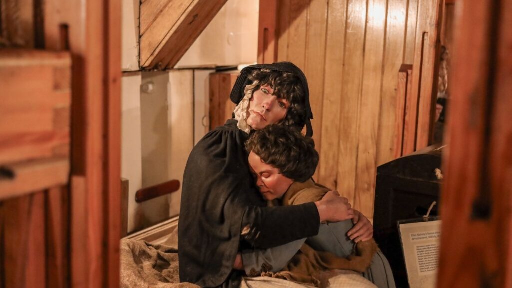 Wax figures of mother and child embracing in a Dublin museum exhibit.