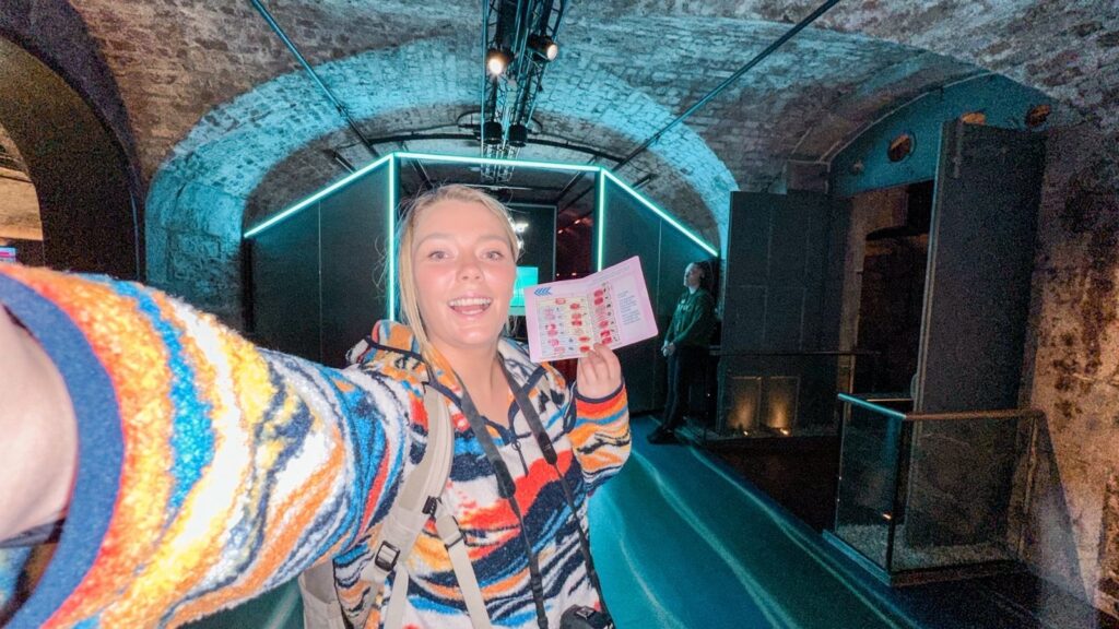 Woman holding a Dublin Pass brochure at a Dublin attraction, underground venue.