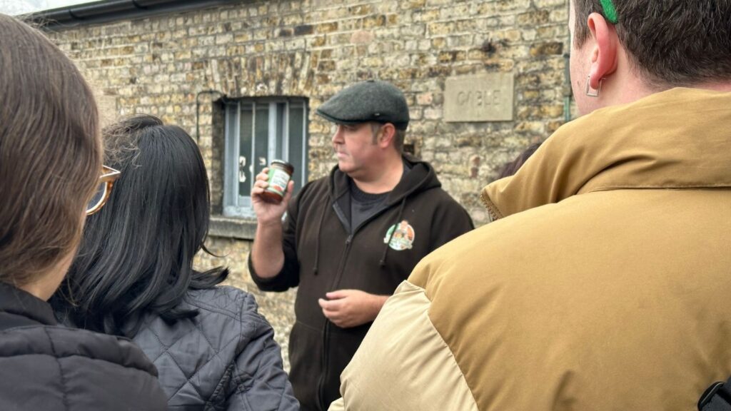 Dublin tour guide holding a jar in front of a brick building.