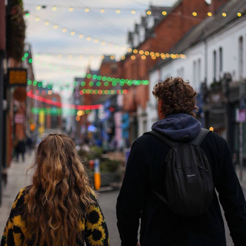 Couple walking down a Dublin street with colorful lights overhead. Dublin attractions.