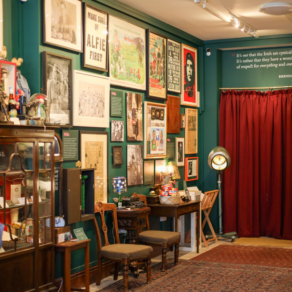 Eclectic room display with vintage posters and memorabilia on green walls.
