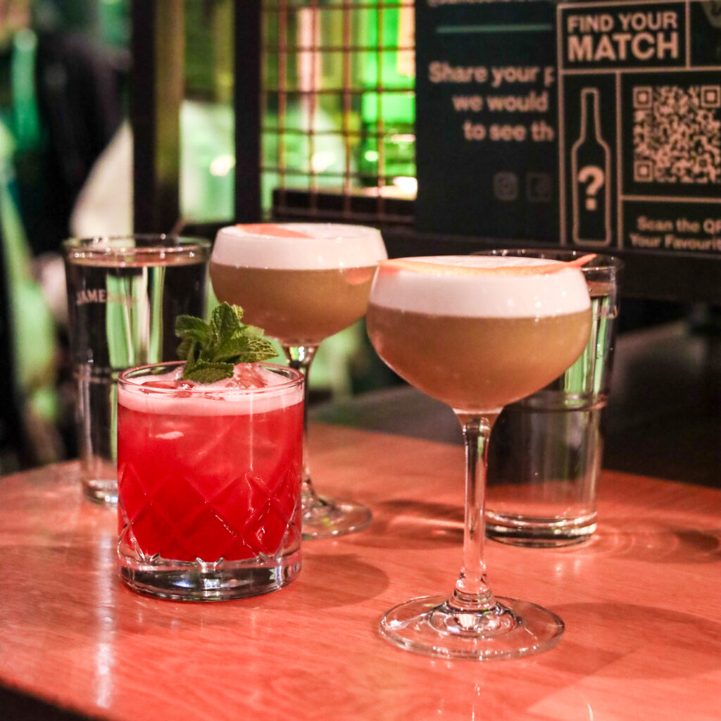 Colorful cocktails on a bar top with fresh garnishes.