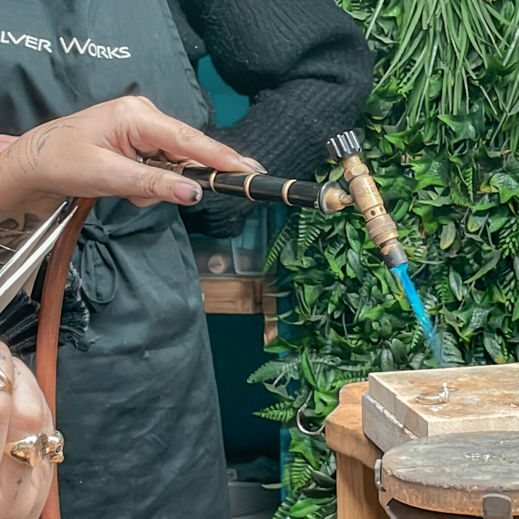 Jeweler soldering silver with a torch during a silverworks tour.