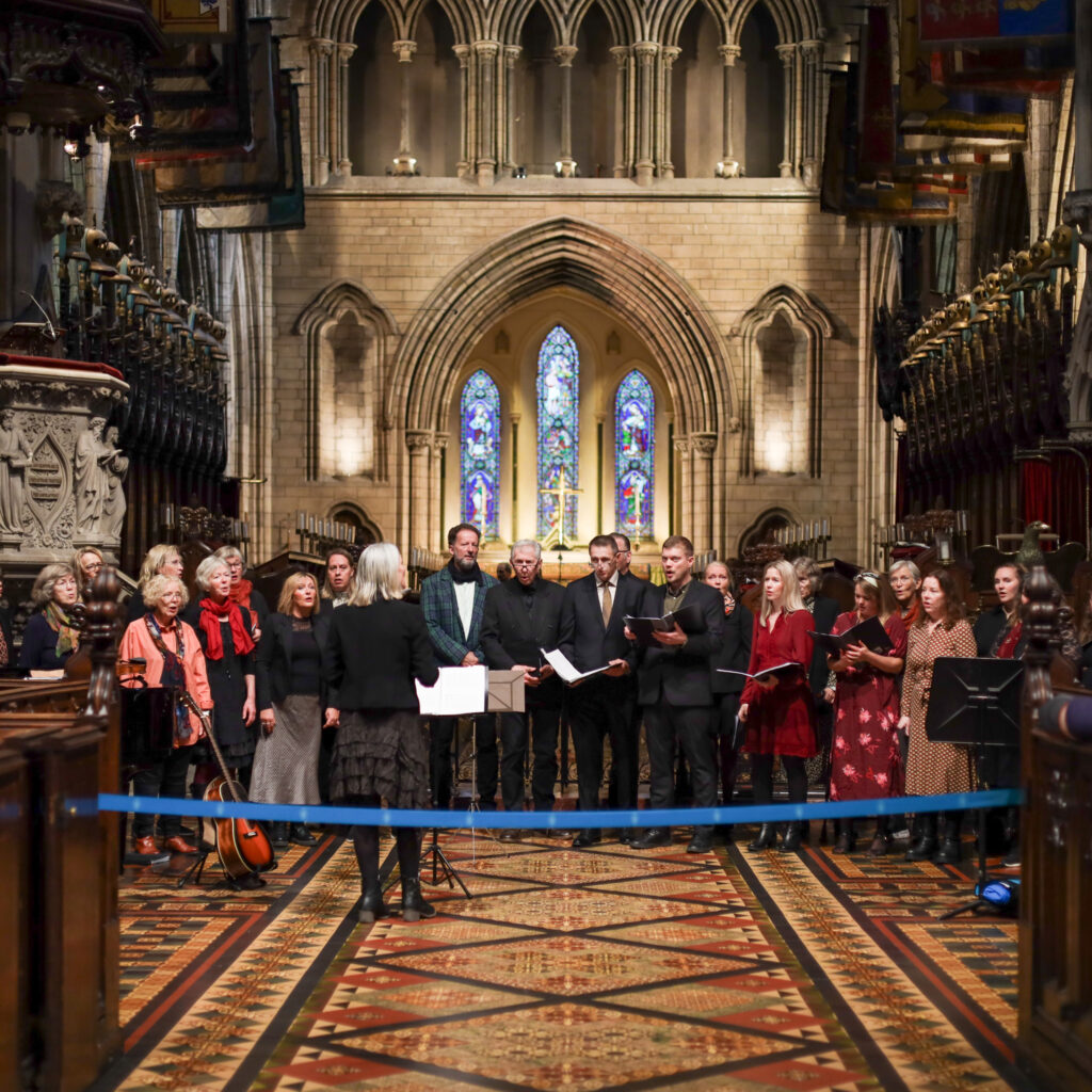 Choir performing in Dublin church with stained glass windows.