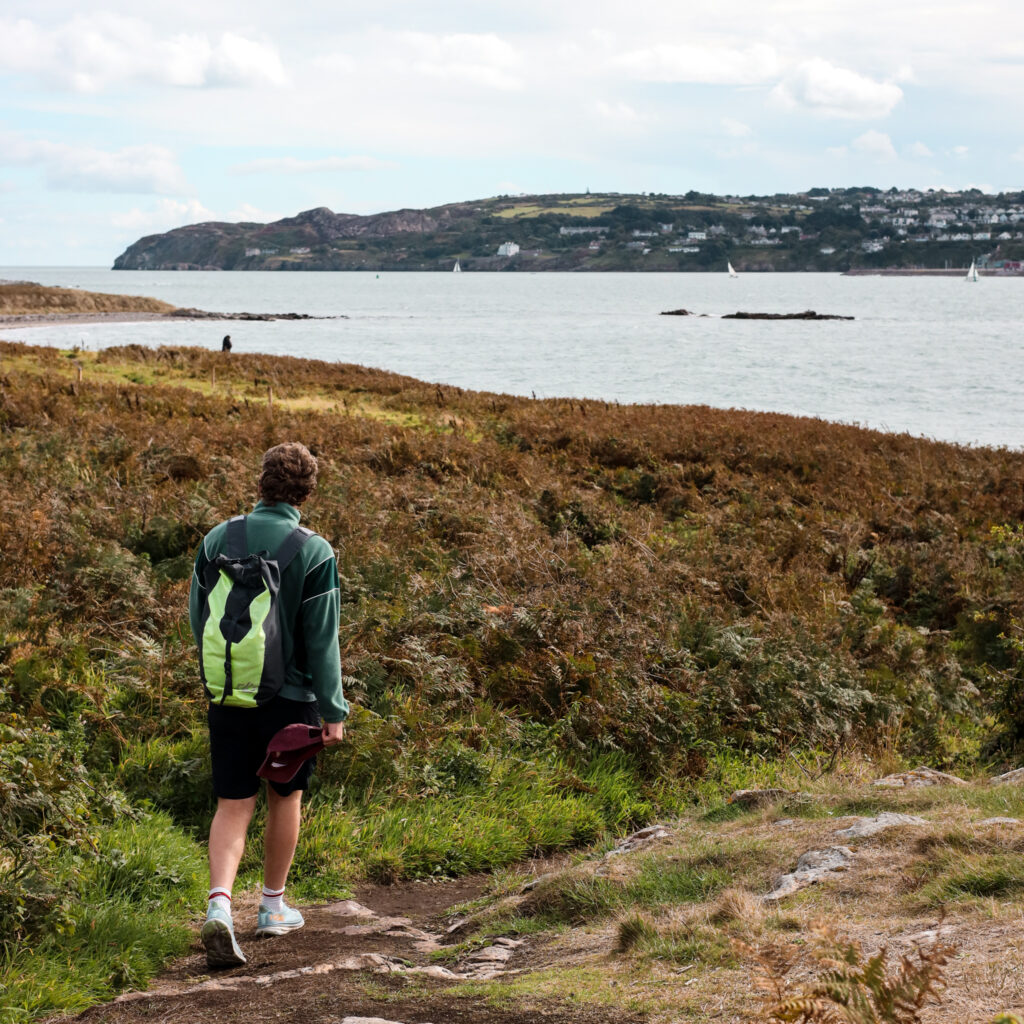 Man hiking near Dublin coastline with a backpack. Dublin attractions.