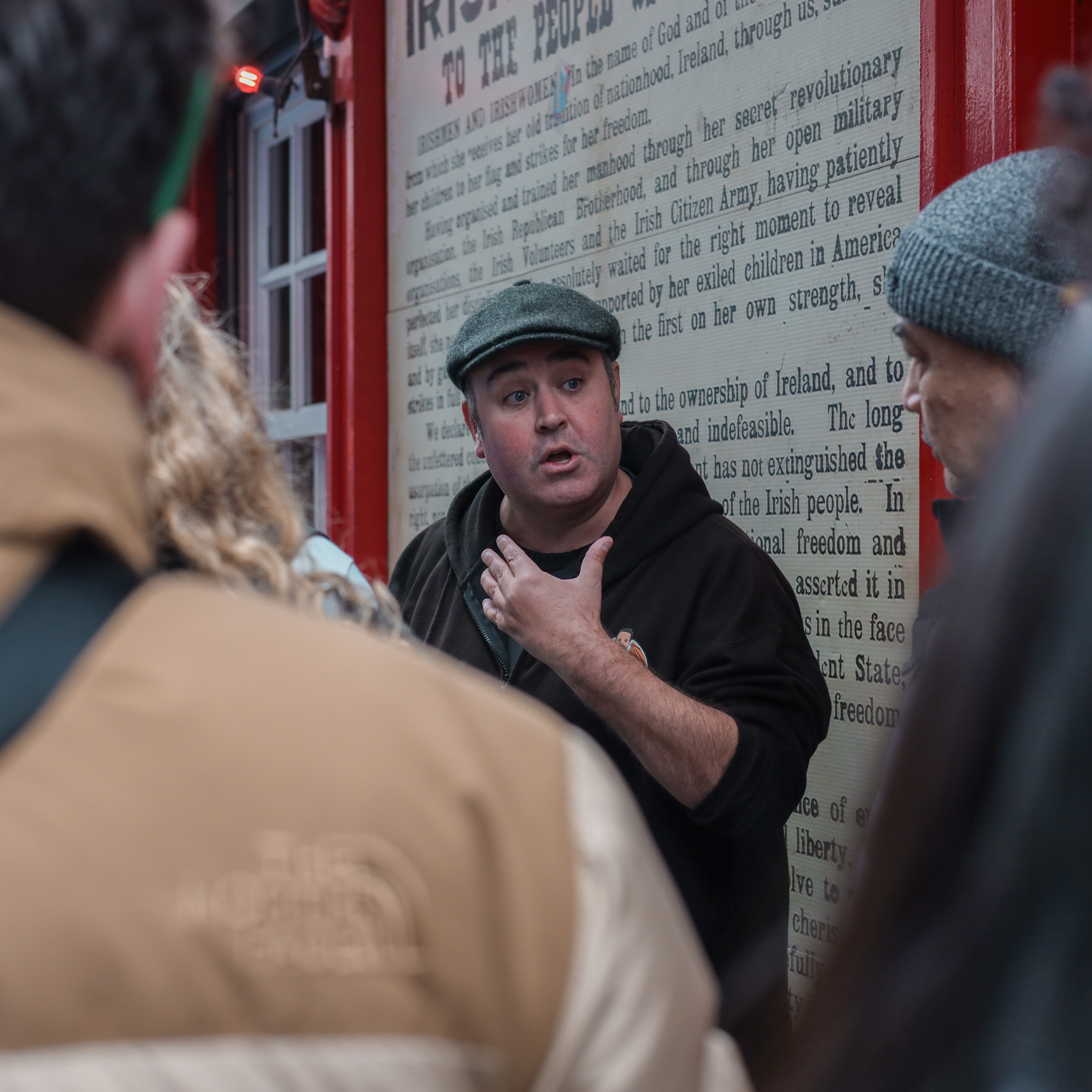 Man in cap speaking in front of Irish history display.