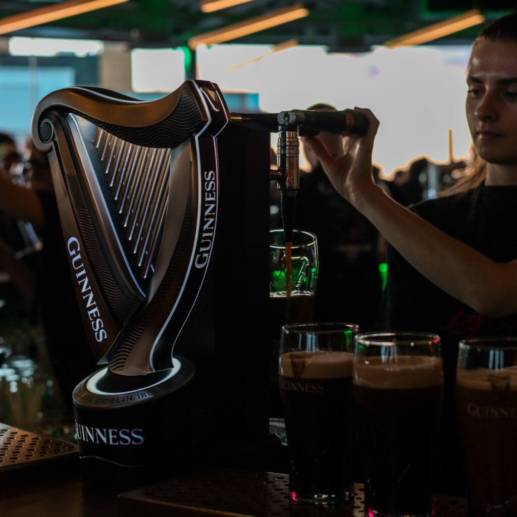 Guinness beer pouring from tap into glass at bar, ready for tours and experiences.