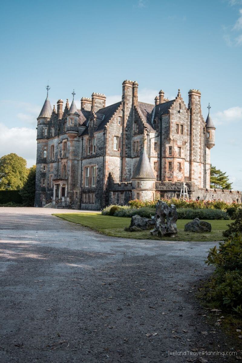 Historic stone castle with turrets and a green lawn Blarney Castle Gardens