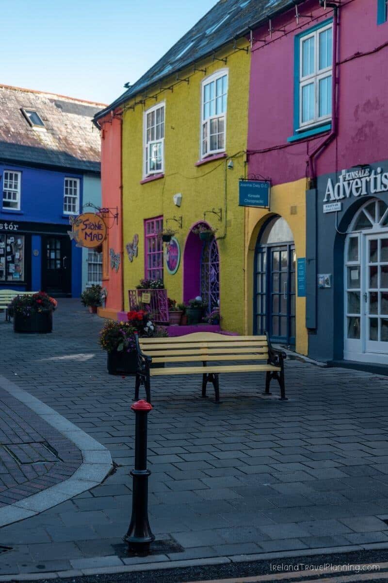 Brightly painted buildings with bench on a cobblestone street in Kinsale town