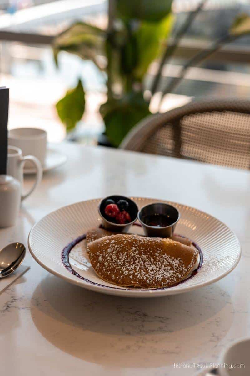 Plate of pancakes with berry sauce and fruit on a marble table