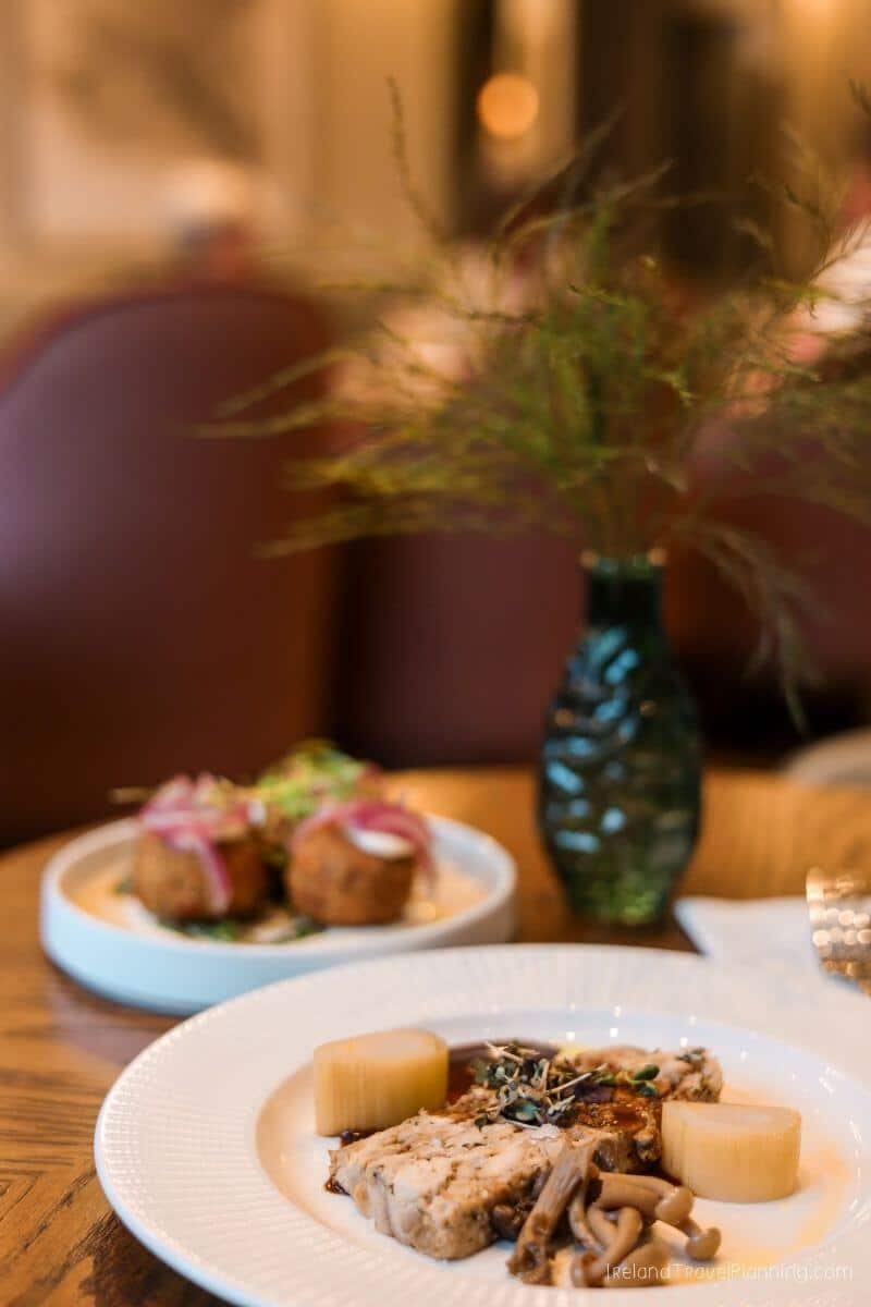 Plates of food on a wooden table with a plant in a vase