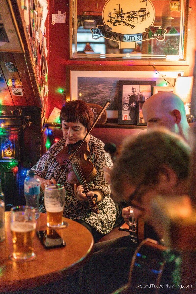 Woman playing violin with men playing guitar in a Cork City pub